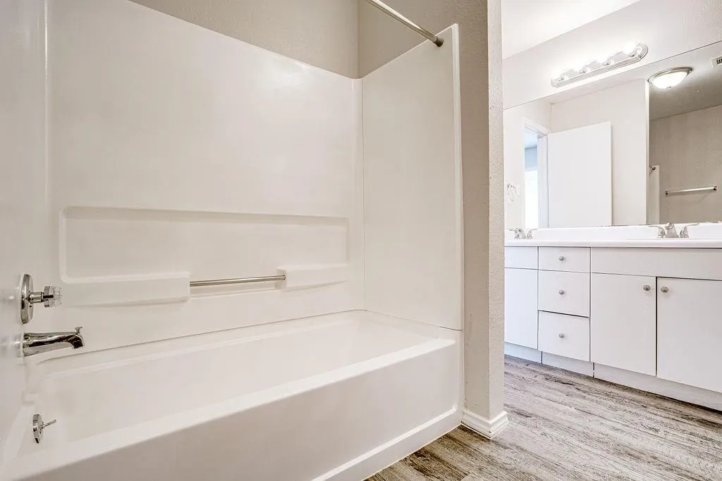 White bathtub with an integrated shower surround and chrome fixtures
