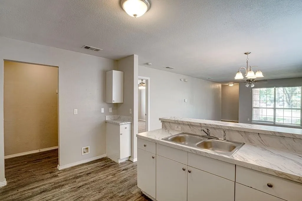 Kitchen features a double-basin stainless steel sink, white cabinetry, and marble-look countertops