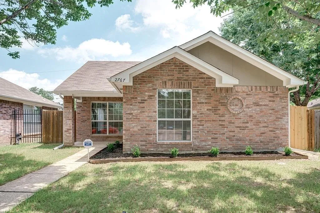 Brick facade home featuring a gabled roofline and front landscaping