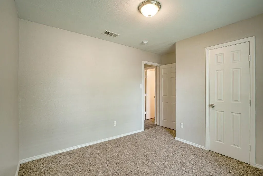 Bedroom featuring neutral-toned walls, textured carpeting, white baseboards, and a semi-flush mount ceiling light fixture