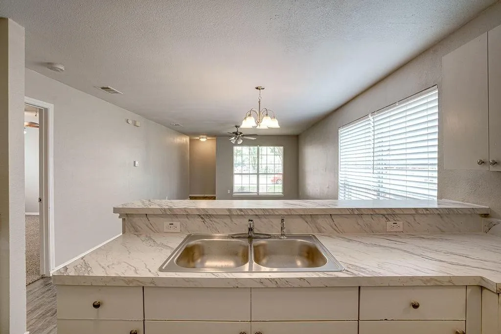 Kitchen counter featuring a double basin stainless steel sink set into a white patterned countertop with a raised bar