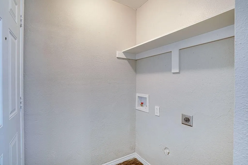 Dedicated laundry area featuring a built-in shelf, appliance hookups, and a paneled white door