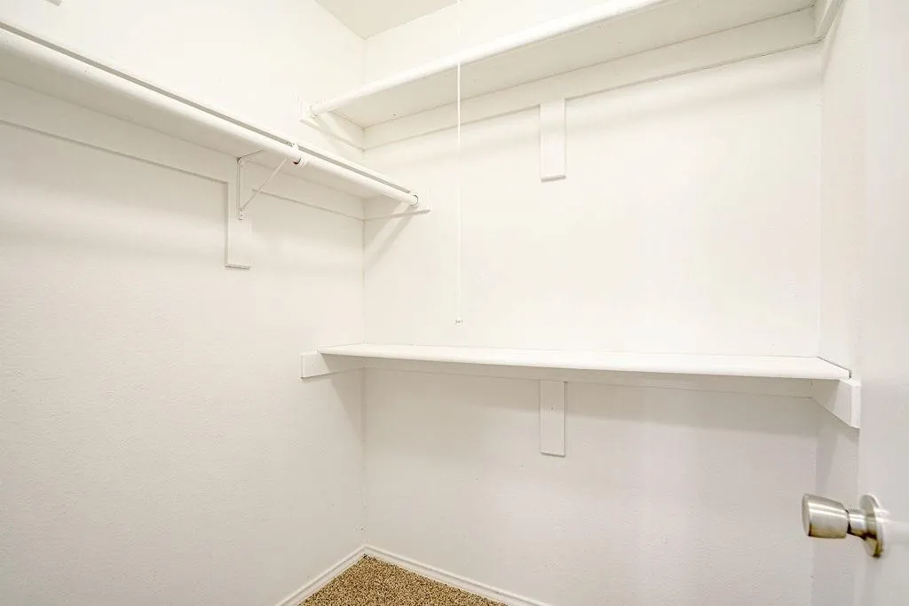 Walk-in closet with white shelving and hanging rods