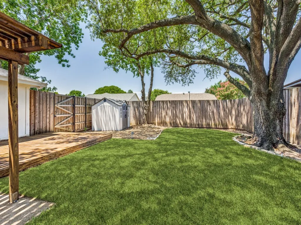 Private backyard featuring a wooden deck, mature tree, and perimeter fencing