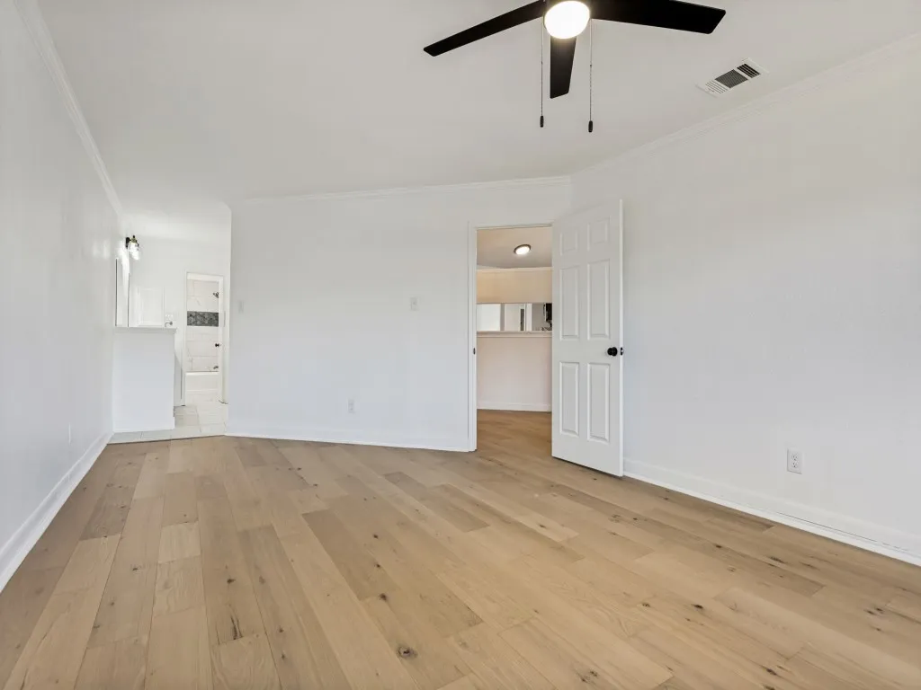 Light wood-finish flooring with white baseboards and crown molding