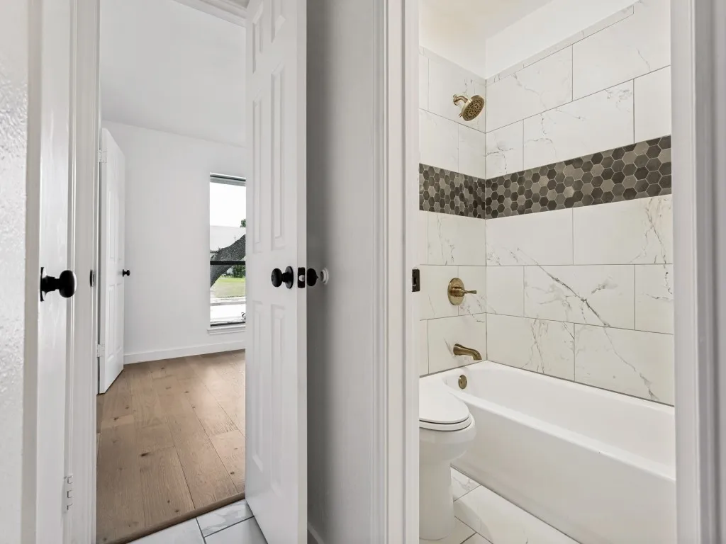 Full bathroom featuring a tub-shower combination with white marble-look subway tile and a decorative mosaic hexagon tile band