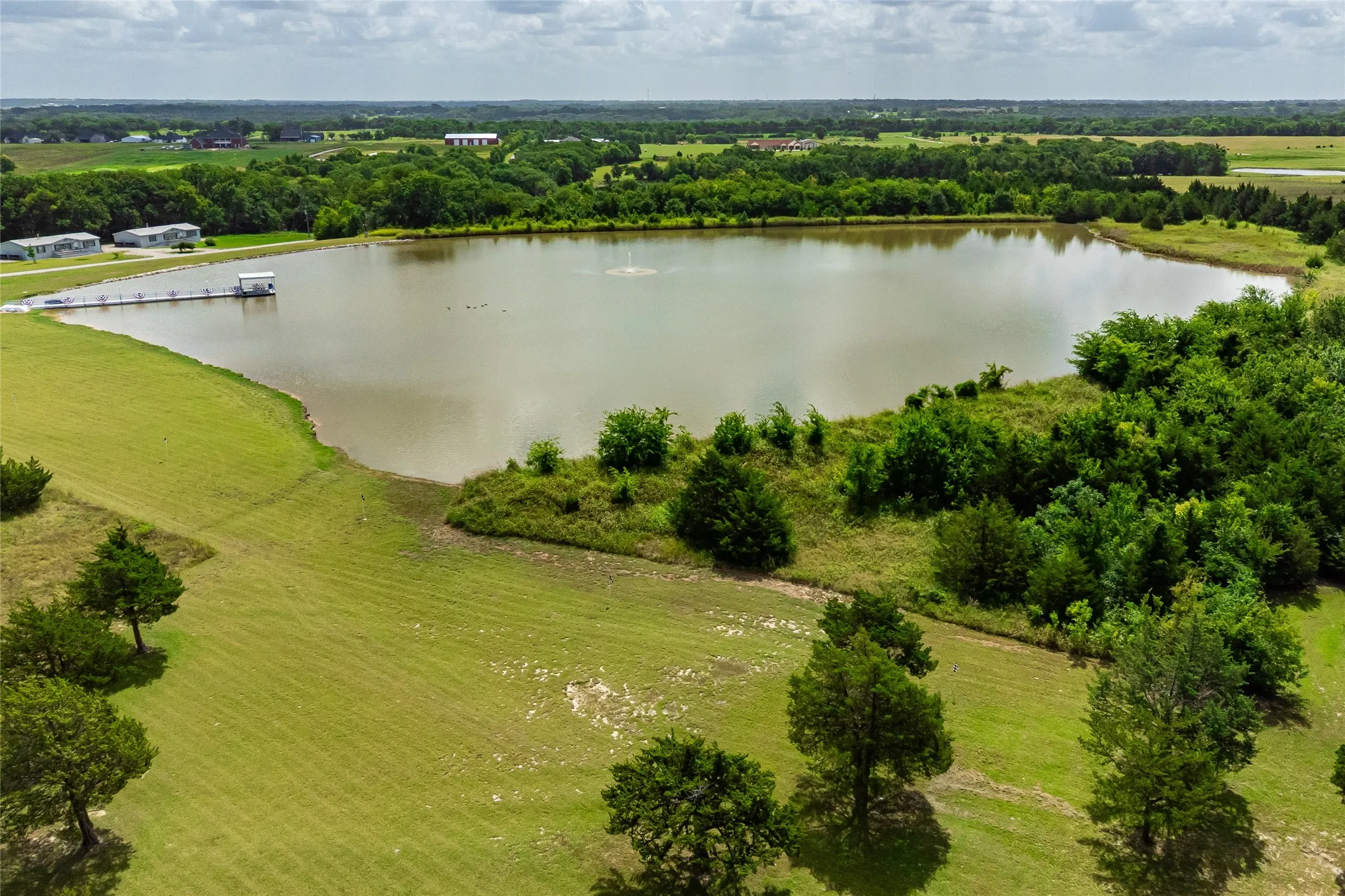 Arial view of Lake Saint Michael which is approximately 40 feet deep at the center, 25 feet deep rip rap shoreline and average depth of 15 feet.  This 10-acre lake is an attractive showstopper with the fountain spray and trees in the background.