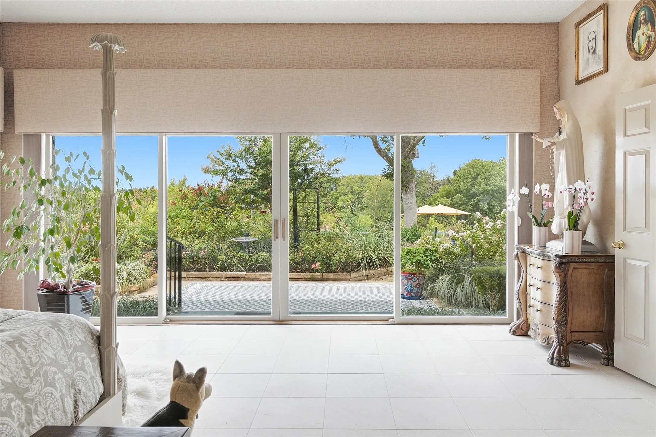 Spacious primary bedroom which can easily accommodate large bedroom furniture set.  Pella liding doors and windows welcome in the light and gorgeous landscaping and views. The flooring is natural Boreal honed unpolished marble 16-inch tile and walls have 12-inch tiles floor to ceiling. The windows have blackout honeycomb solid horizontal shade on the south Pella window.