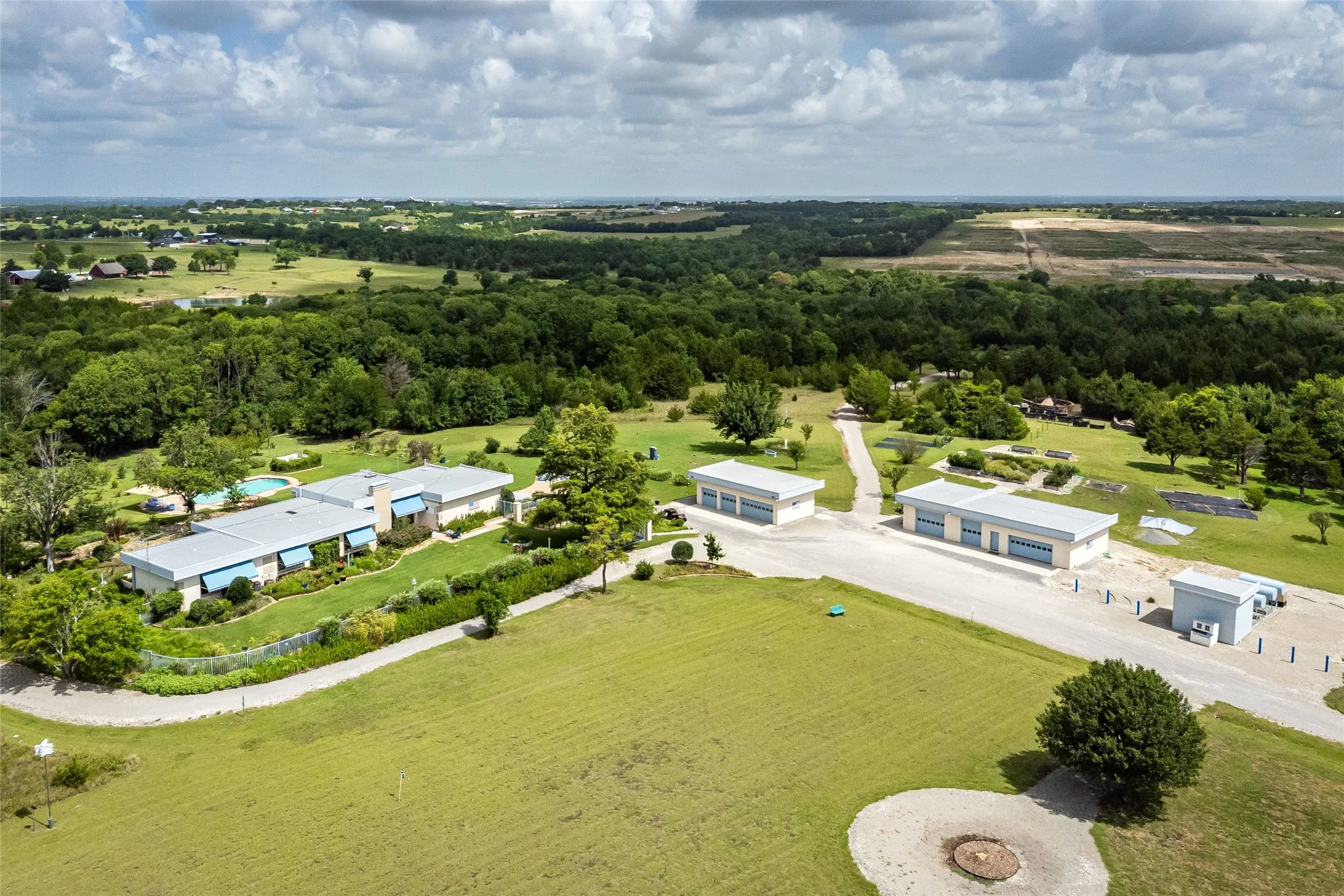 Aerial view of the main residence, the two garage structures permitting 4 car spaces each for a total of 8-car spaces & a pumphouse.