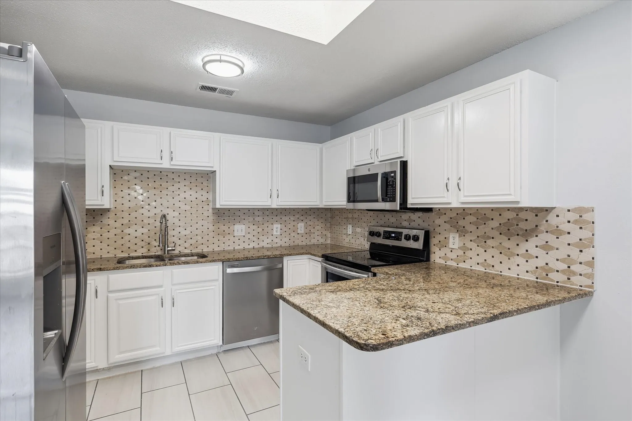Updated open kitchen with granite countertops, stainless steel appliances, and luxury vinyl plank flooring.