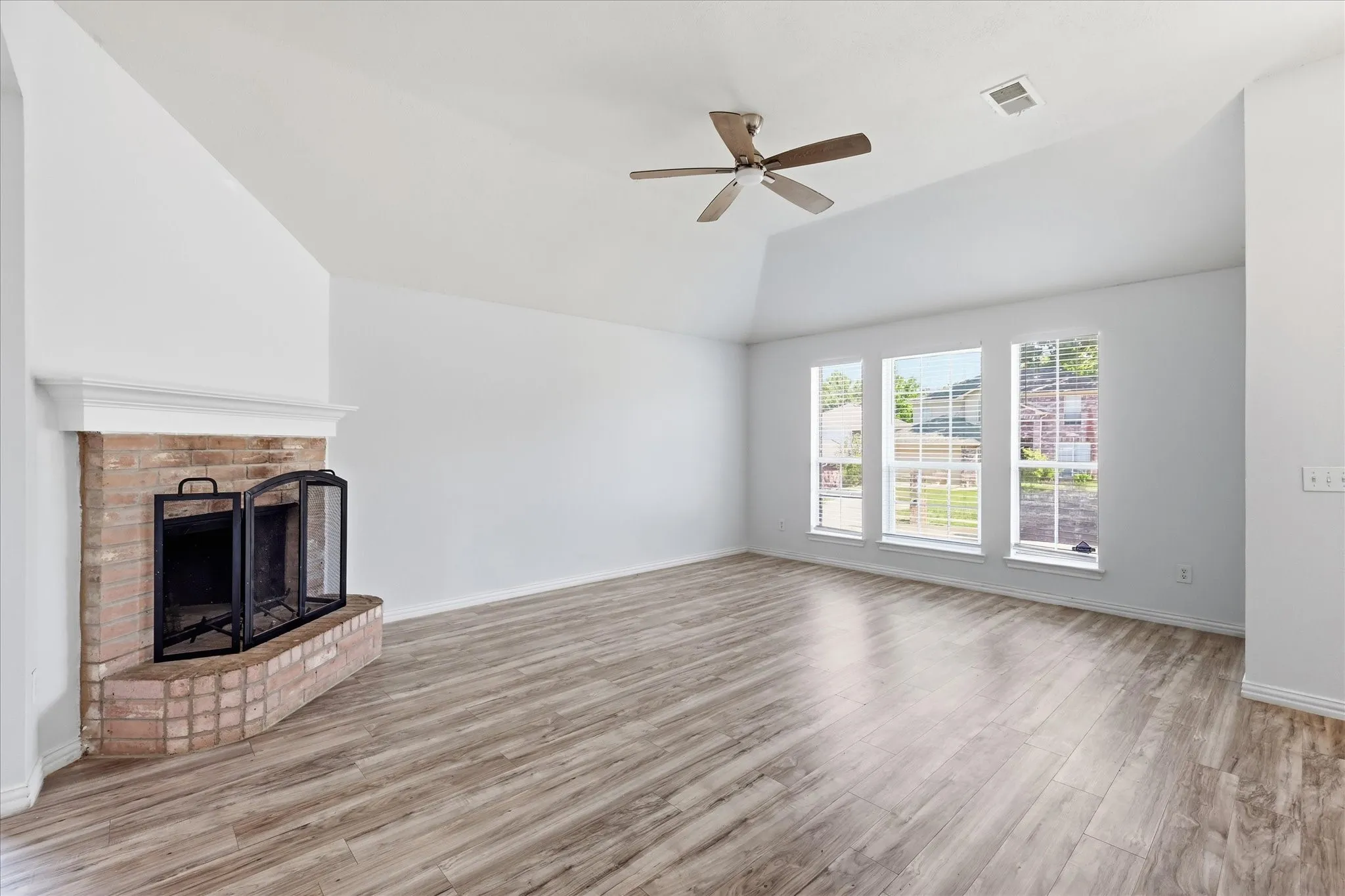 Spacious 15x18 living room with high ceilings, a fireplace, and luxury vinyl plank flooring.