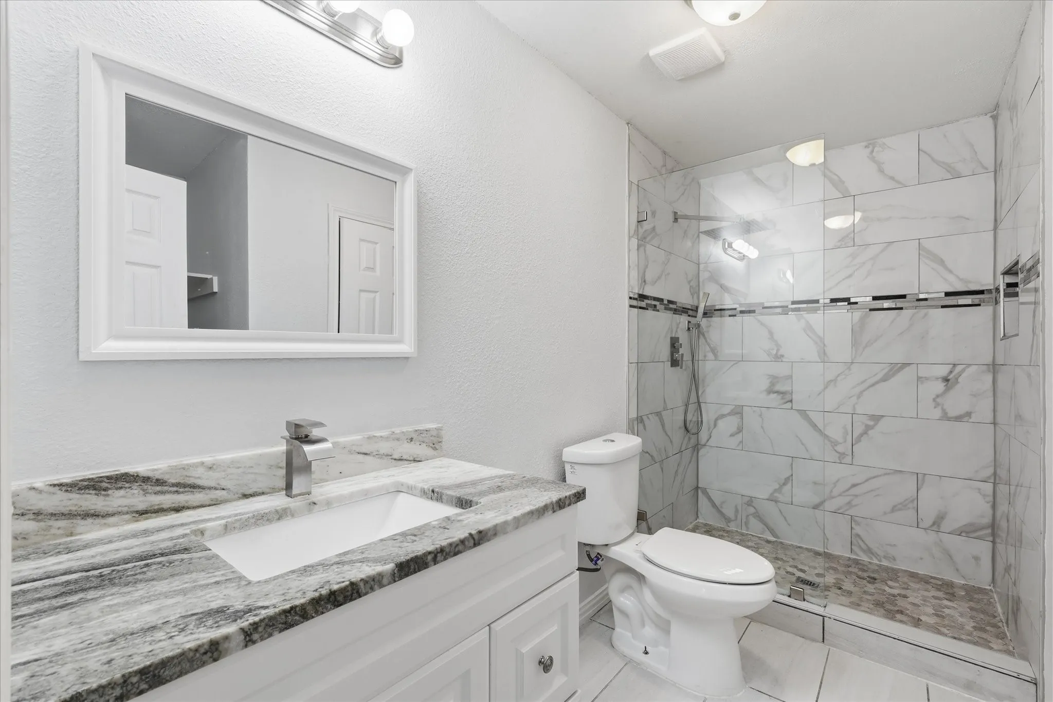 Remodeled en-suite primary bath featuring an oversized shower with frameless glass and a granite vanity with a square sink.