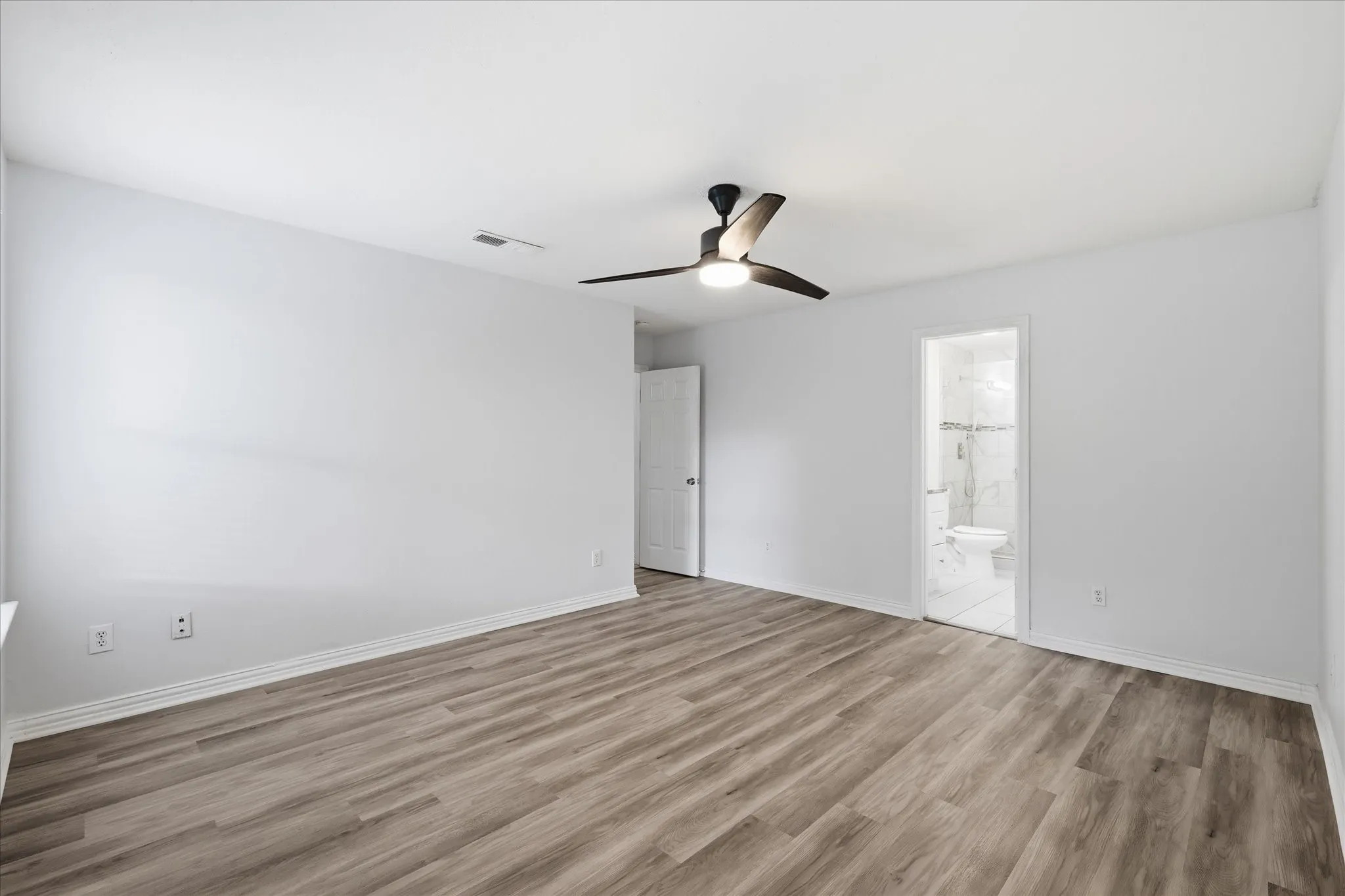 Open primary suite with luxury vinyl plank flooring and ample space for a king-sized bed.