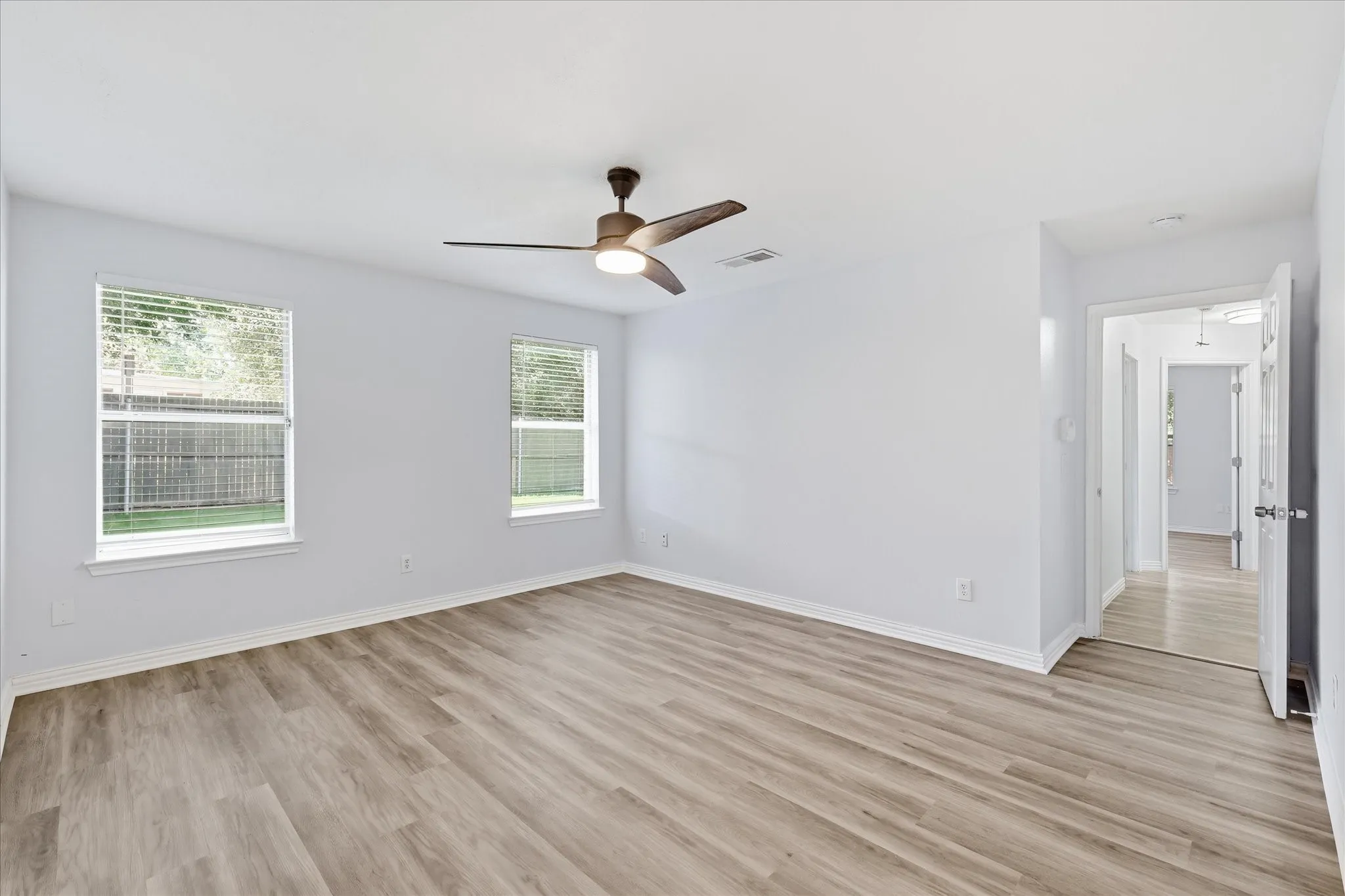 Open primary suite with luxury vinyl plank flooring and ample space for a king-sized bed.