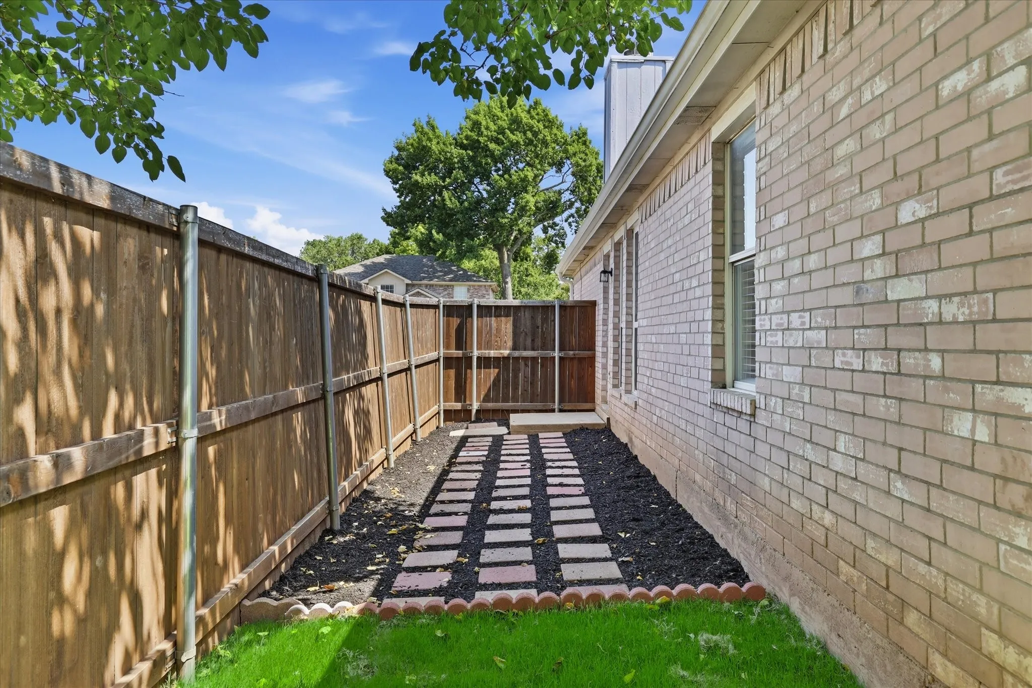 Back view showing a manicured path leading into a spacious, grassy, non-HOA backyard.