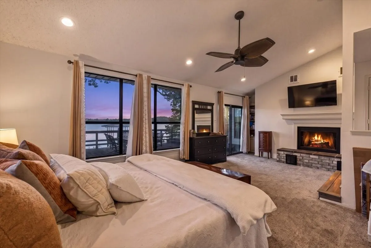 Waterside primary bedroom with wood burning fireplace, access to outside deck.