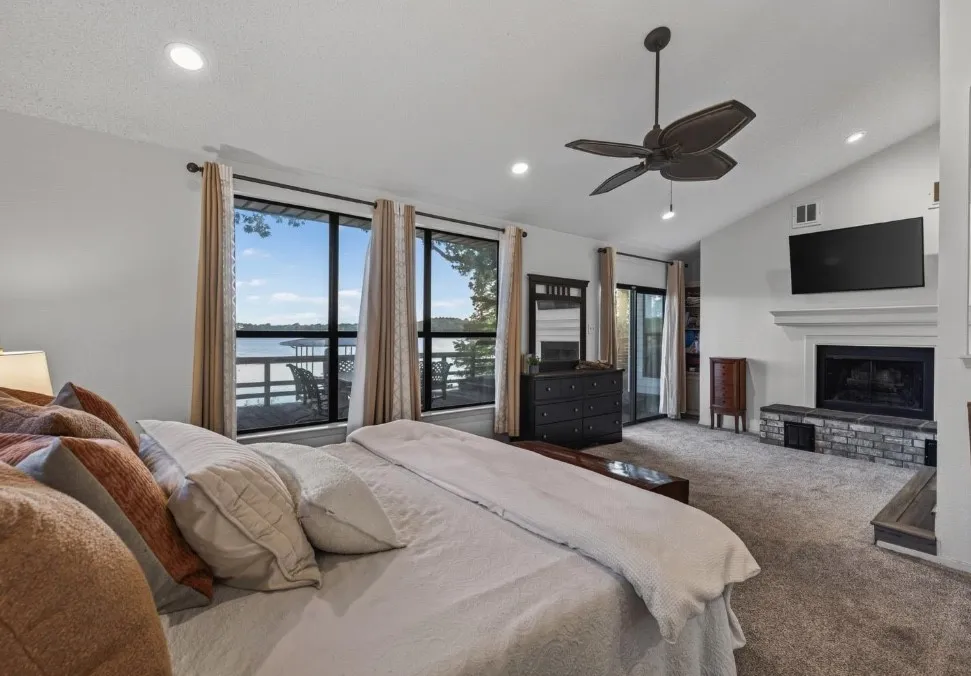 Waterside primary bedroom with wood burning fireplace, with access to outside deck.