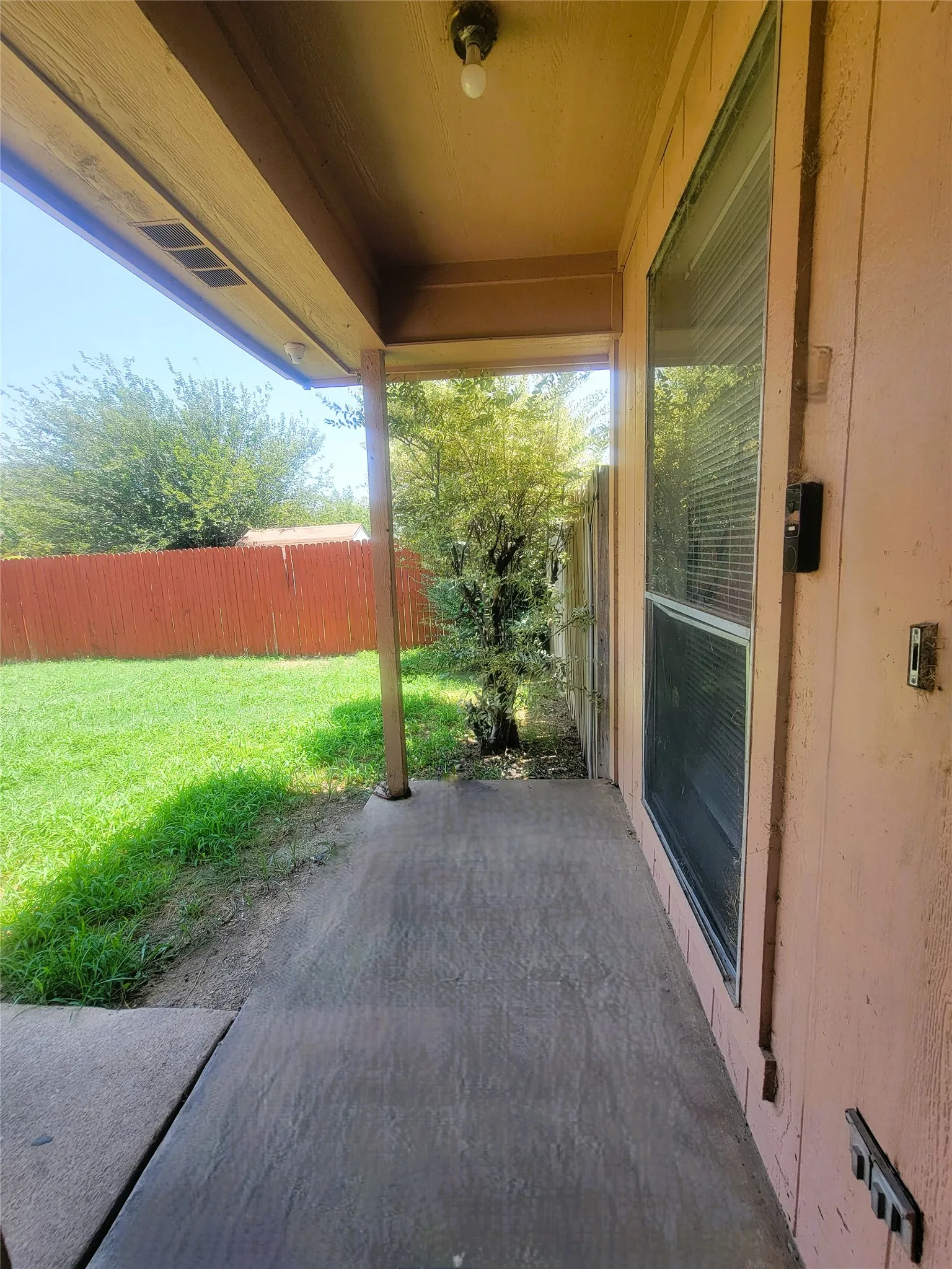 Covered concrete patio with a painted ceiling, supported by a single pillar