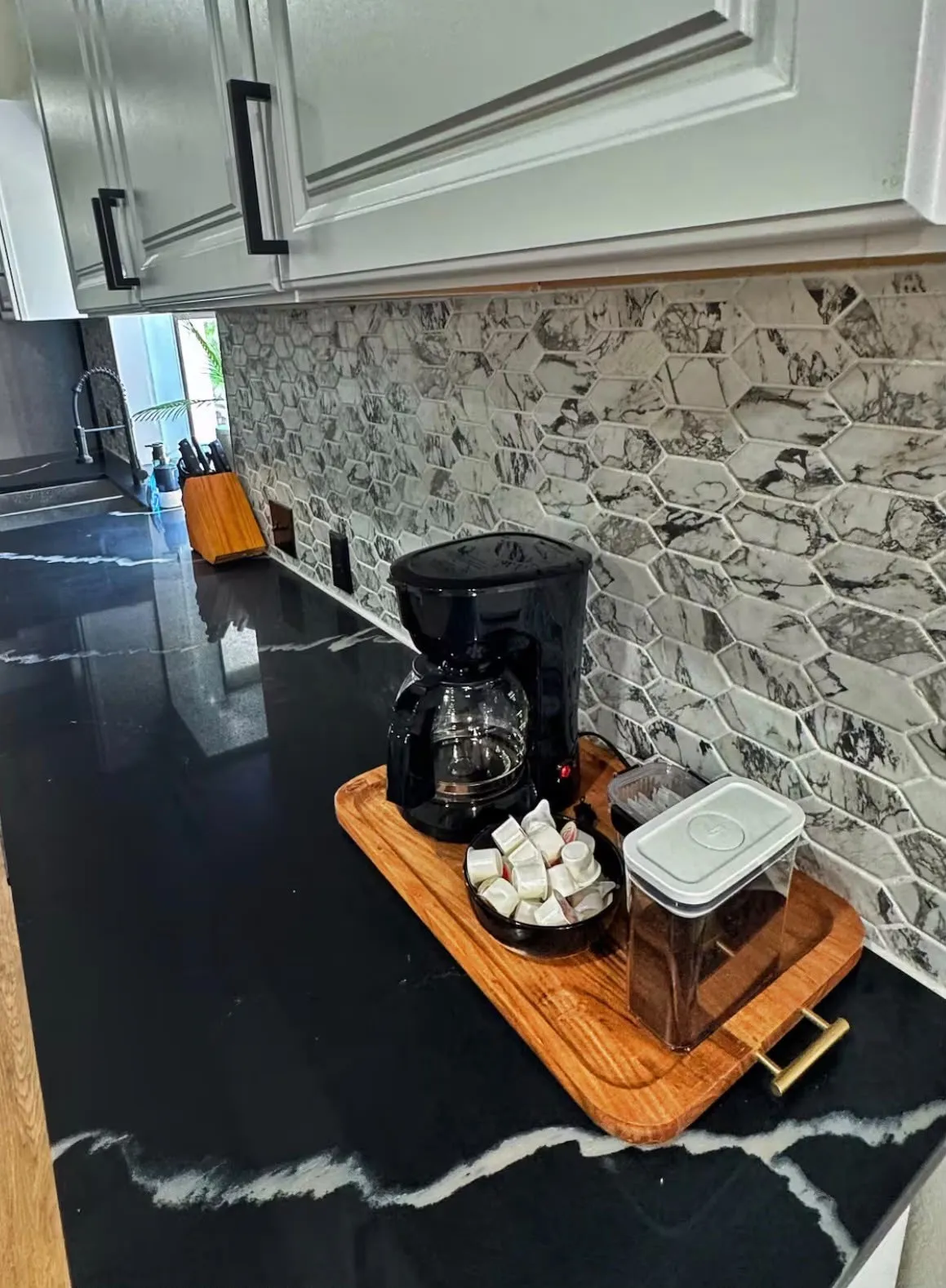 Black countertop with white veining, complemented by a mosaic hexagon tile backsplash