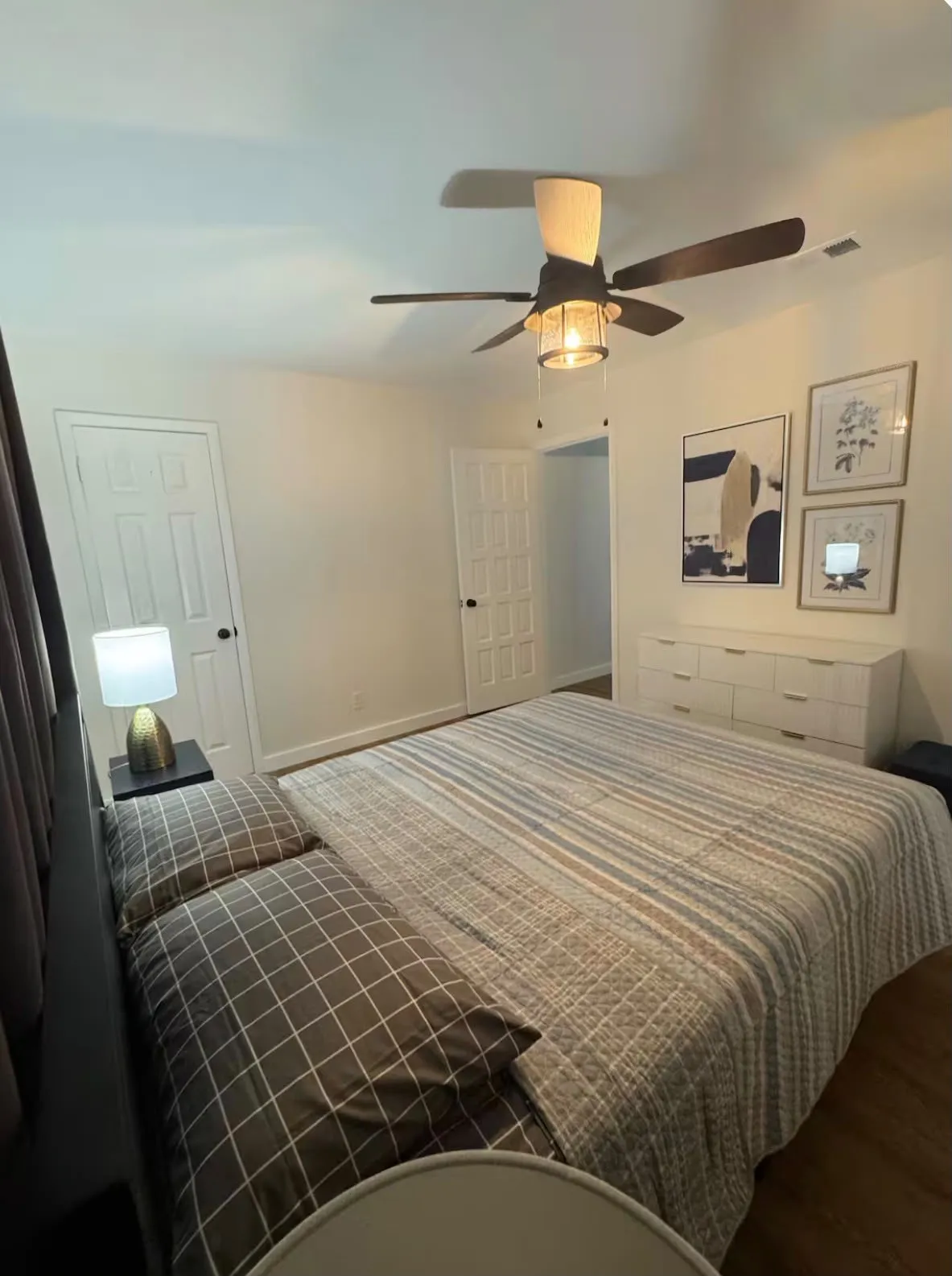 Spacious interior room featuring white walls, wood-finish flooring, and a modern ceiling fan with integrated lighting