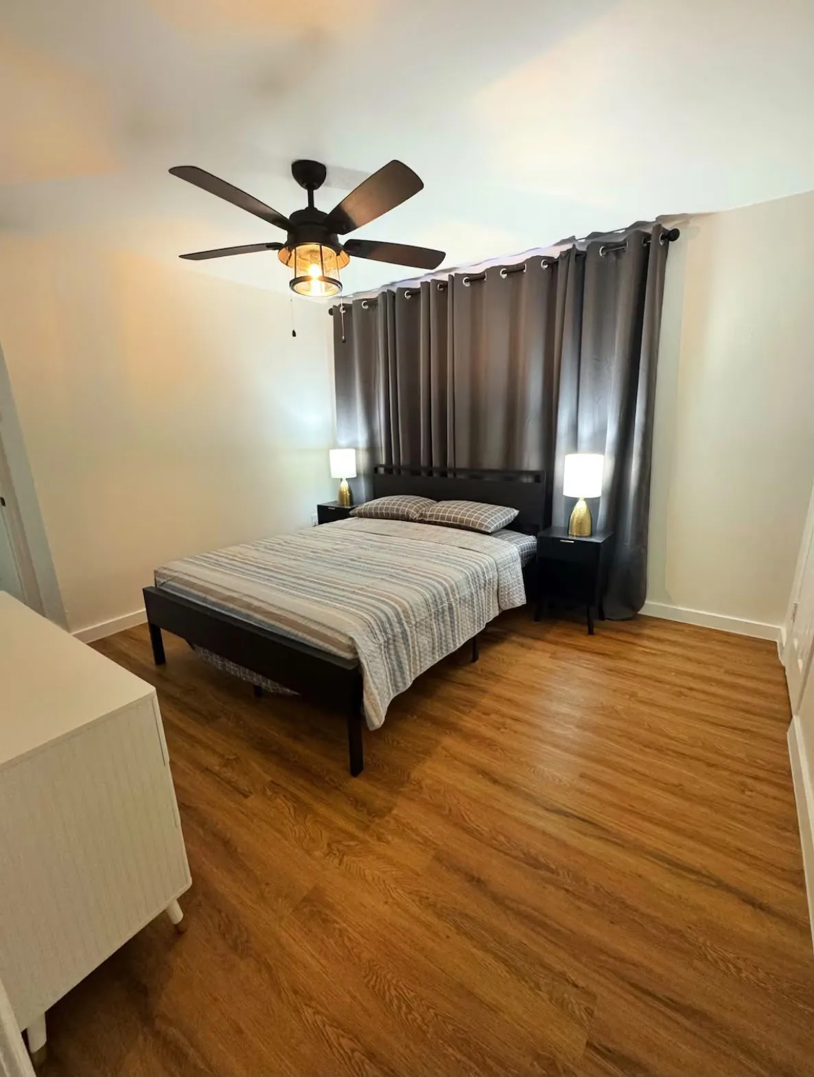 Room featuring wood-finish flooring, a ceiling fan with integrated lighting, and neutral wall tones