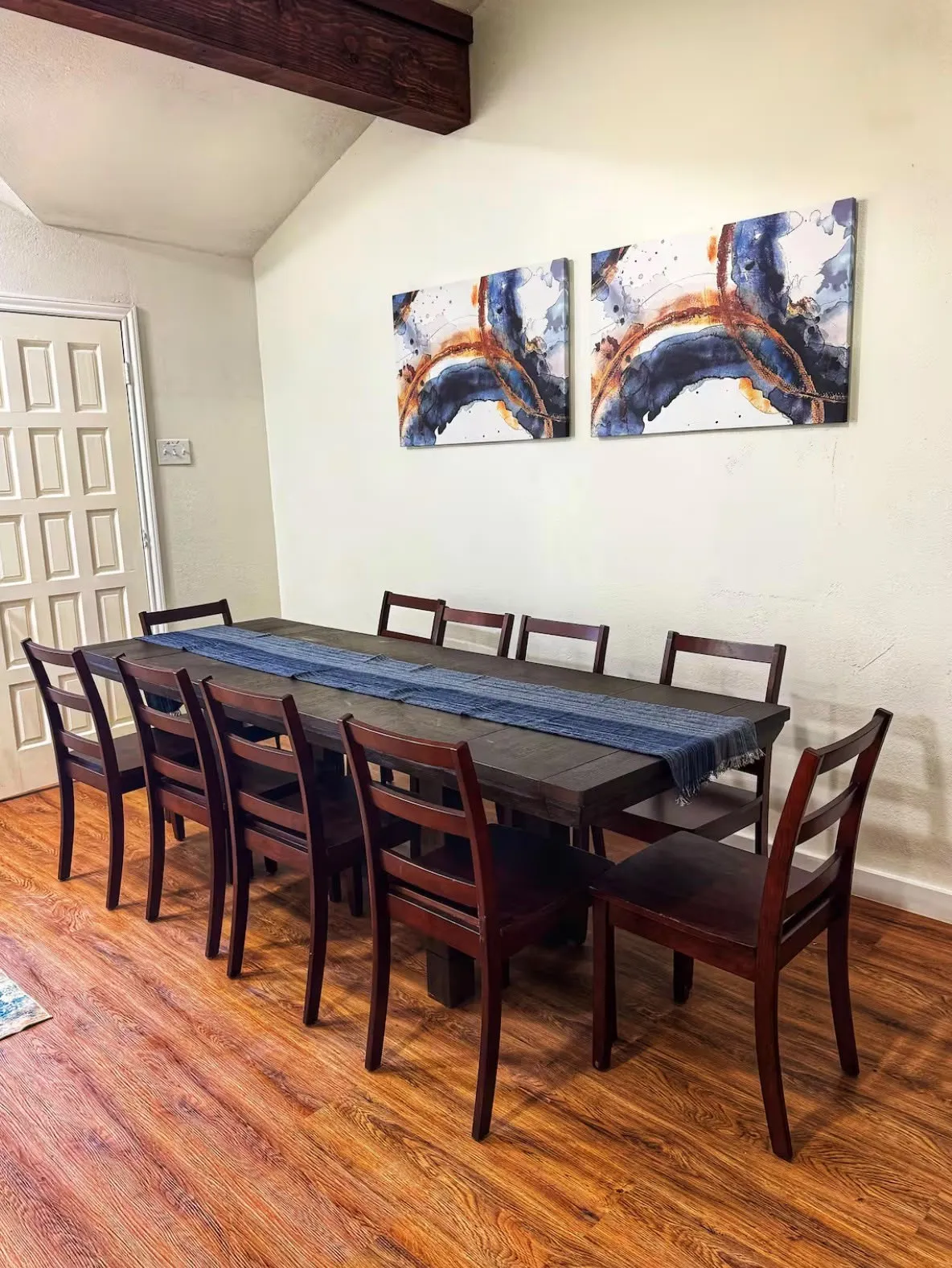 Dining area featuring wood-finish flooring, a vaulted ceiling, and an exposed wood beam