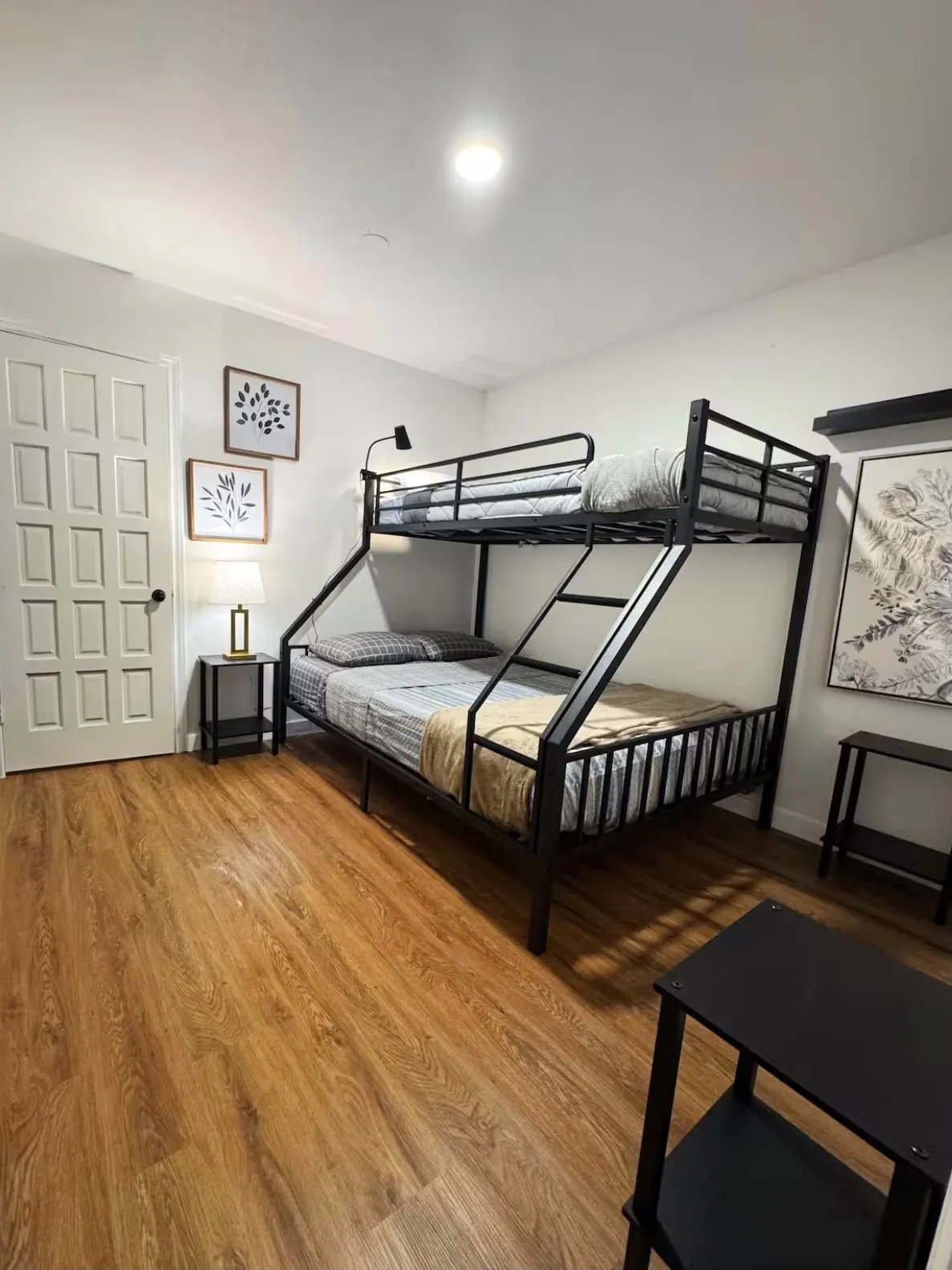 Spacious bedroom featuring dual bunk bed frames with metal construction, wood-finish flooring throughout, recessed ceiling lighting, and ample room for additional furnishings