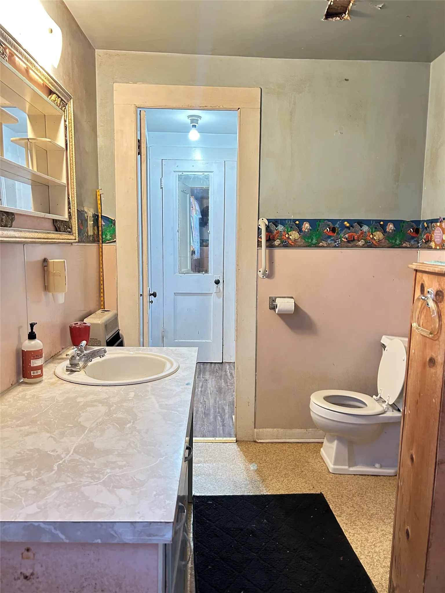  This is your primary bathroom with a sink, formica counter, commode, storage, and vinyl flooring.