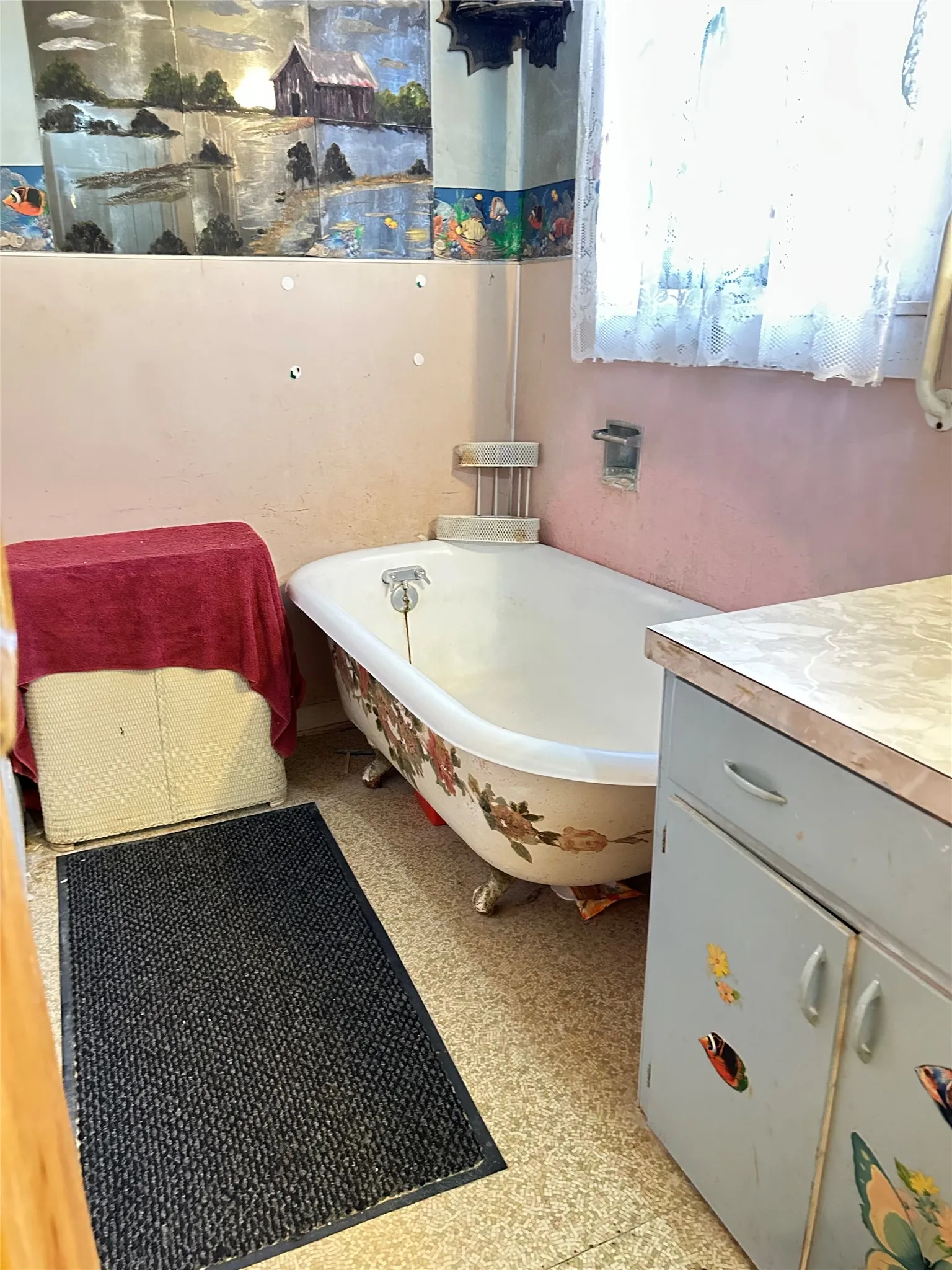 A wonderfully decorated claw foot bathtub adds mood to this bathroom. There is also cabinet storage area under the sink.