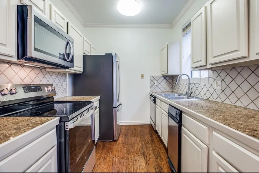 Galley kitchen featuring wood-finish flooring, light-toned cabinetry, and granite-look countertops