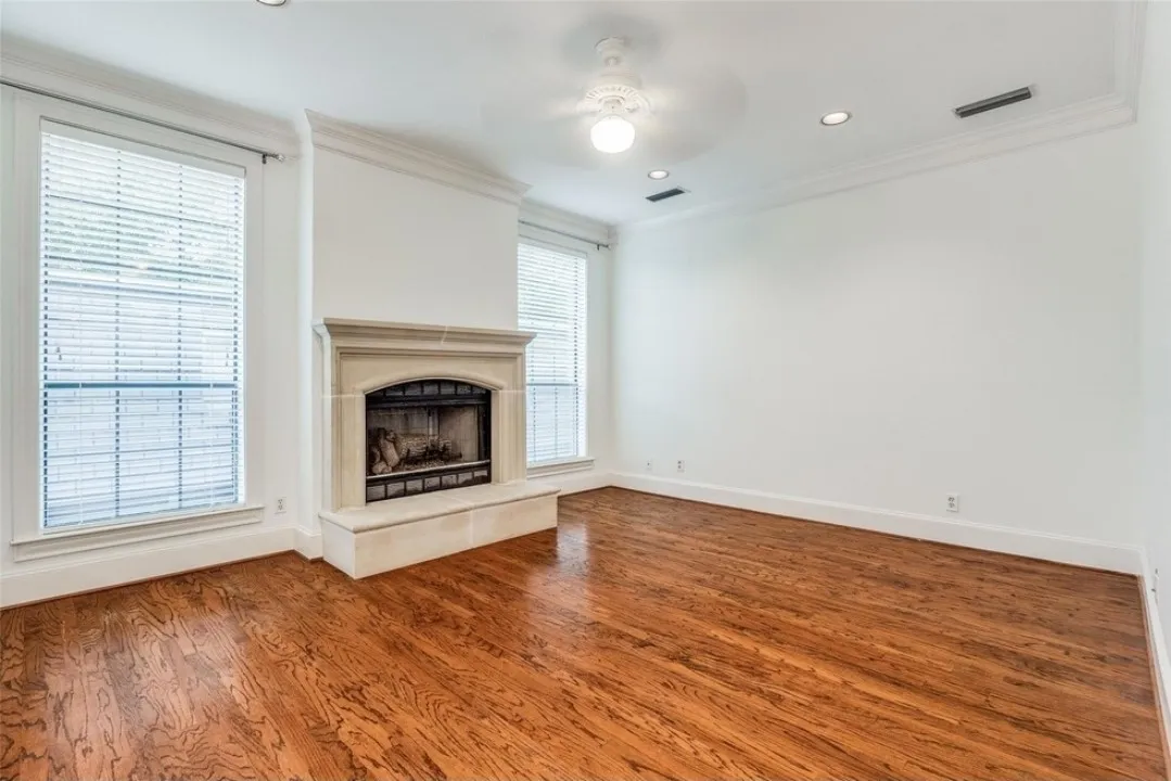 Hardwood flooring with a stone-clad fireplace and hearth