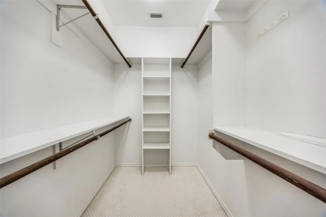 Walk-in closet with carpet flooring, built-in shelving, dual hanging rods, and upper storage shelves