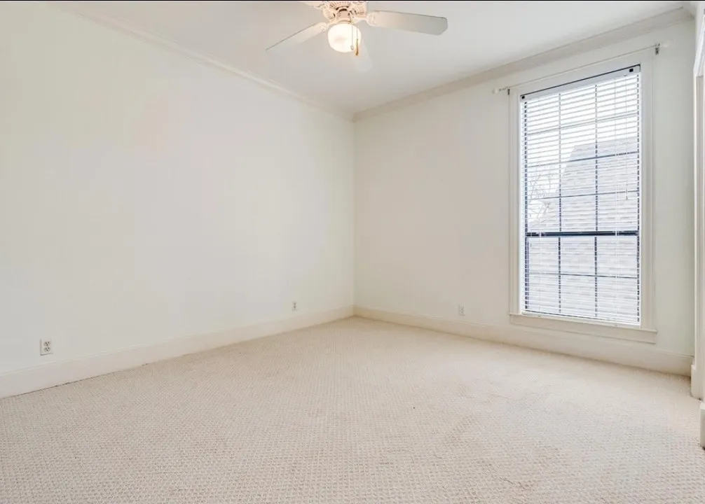 Room featuring a white ceiling fan with integrated lighting, recessed window with blinds, light-toned carpeting, and white baseboards