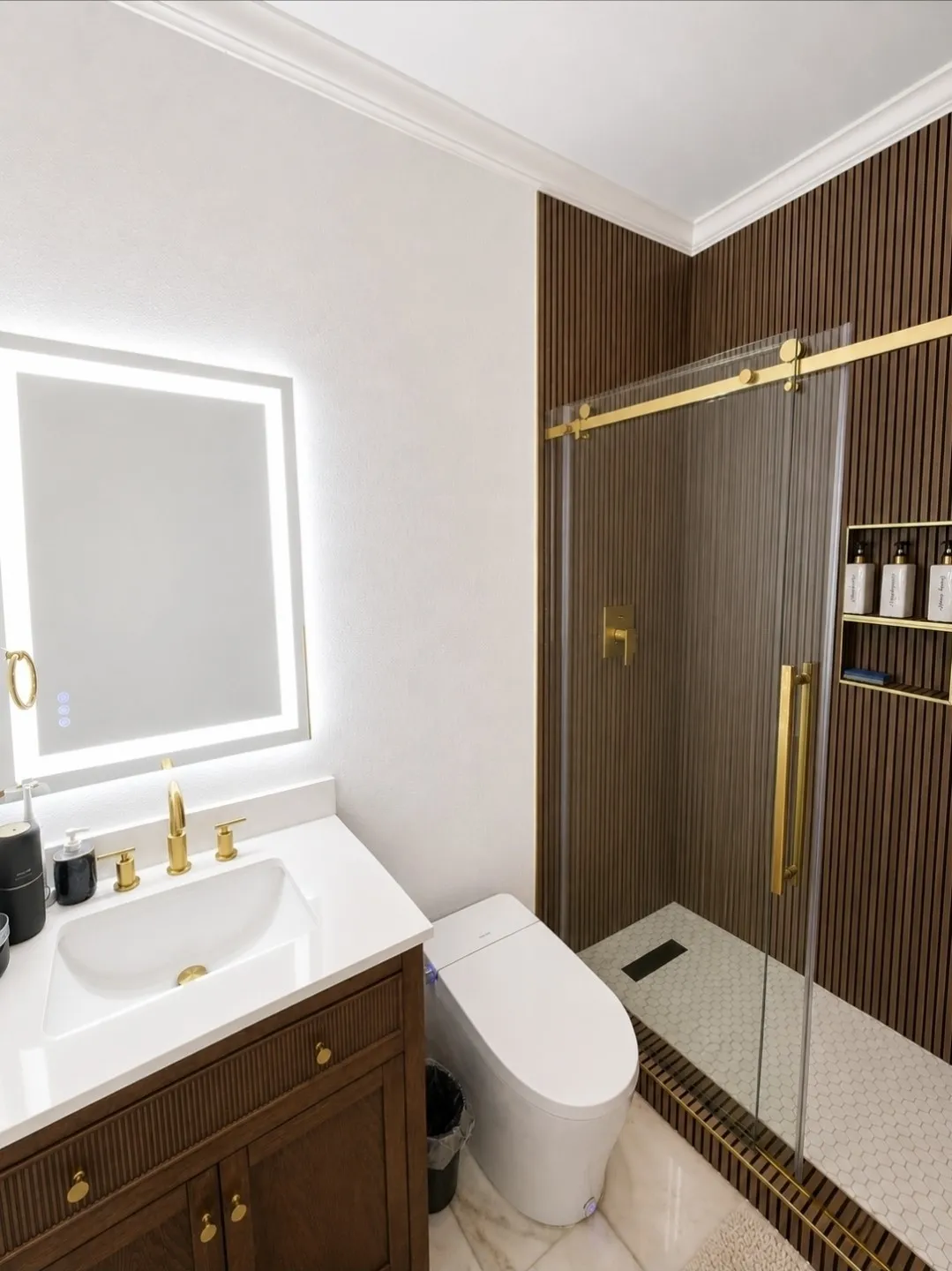 Modern bathroom featuring a wood-finish vanity with a white countertop and gold-tone fixtures