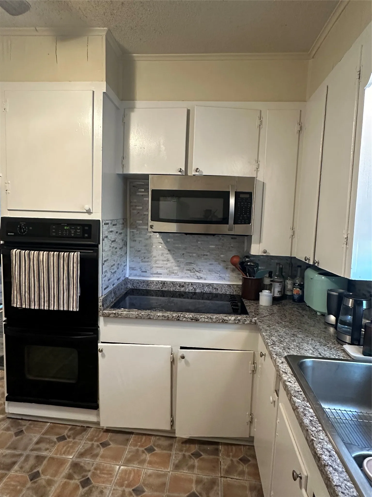 Kitchen featuring white cabinetry, built-in double oven, stainless steel microwave, integrated cooktop, and granite countertops