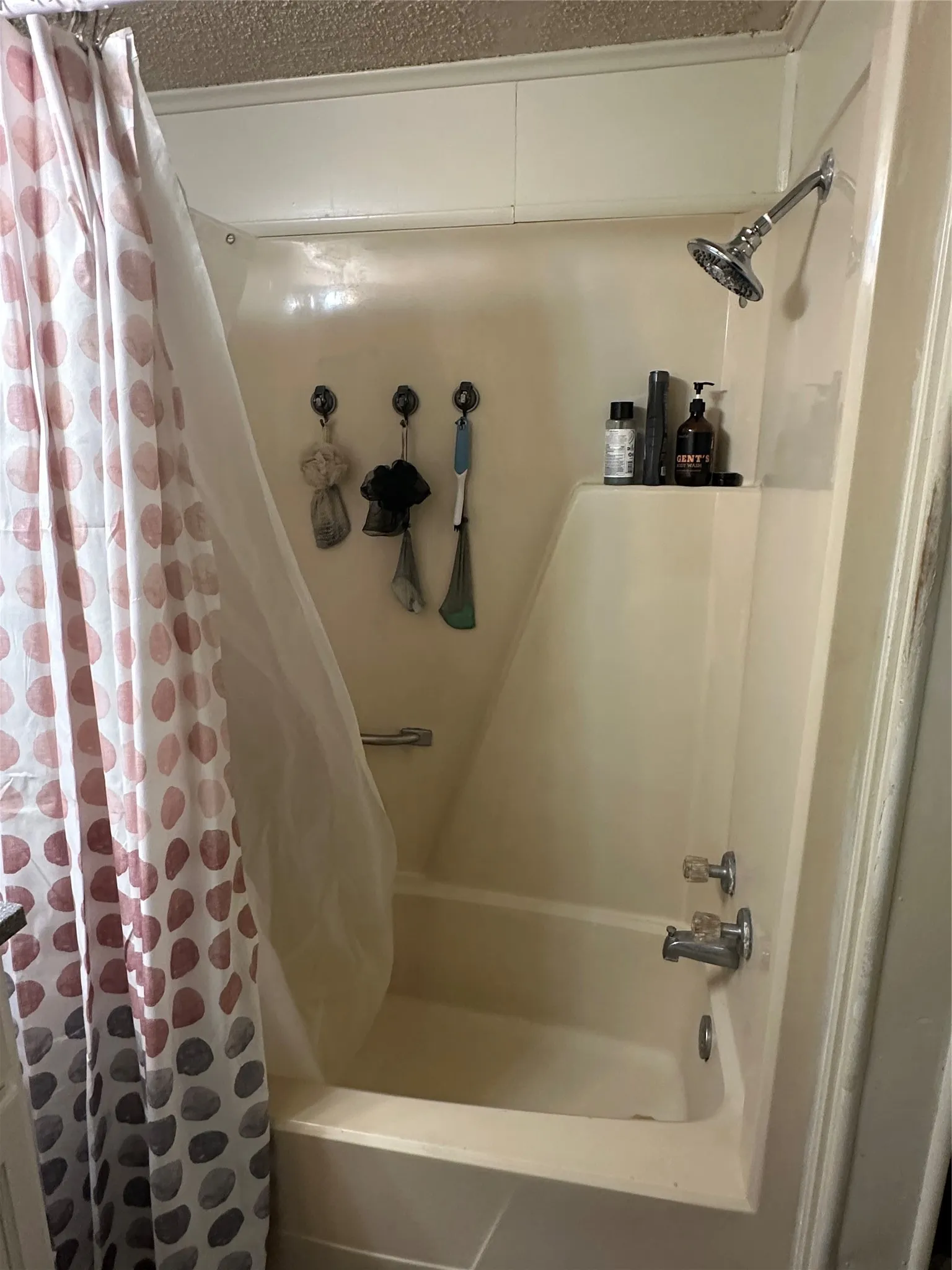 Fiberglass tub and shower combination featuring a chrome showerhead and faucet fixtures