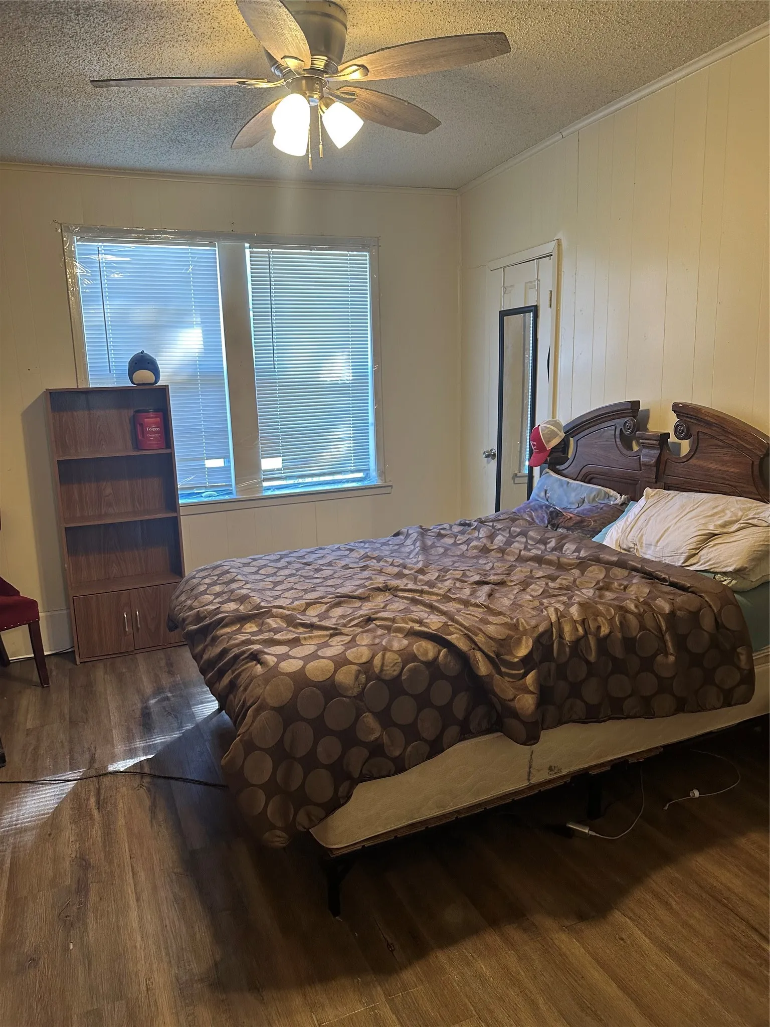Bedroom featuring wood-finish flooring, a ceiling fan with integrated lighting, and two windows with horizontal blinds