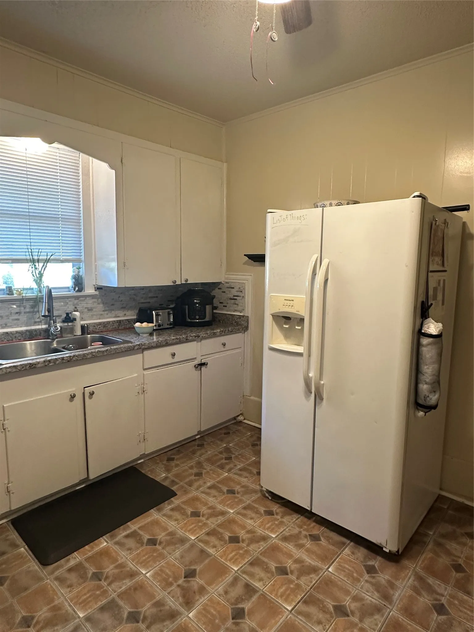 Kitchen featuring white cabinetry, granite countertop, a tile backsplash
