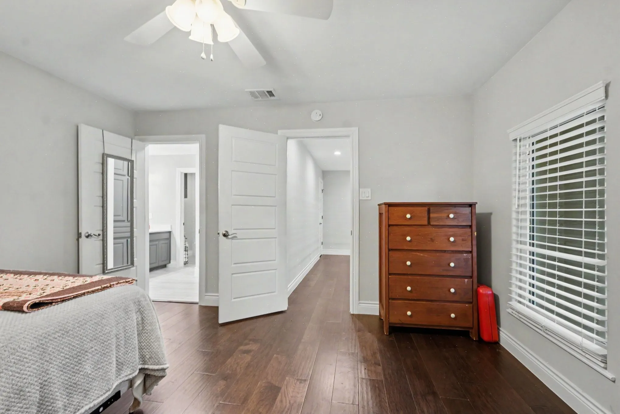 Spacious room featuring wood-finish flooring, light grey wall paint, and a ceiling fan with integrated lighting