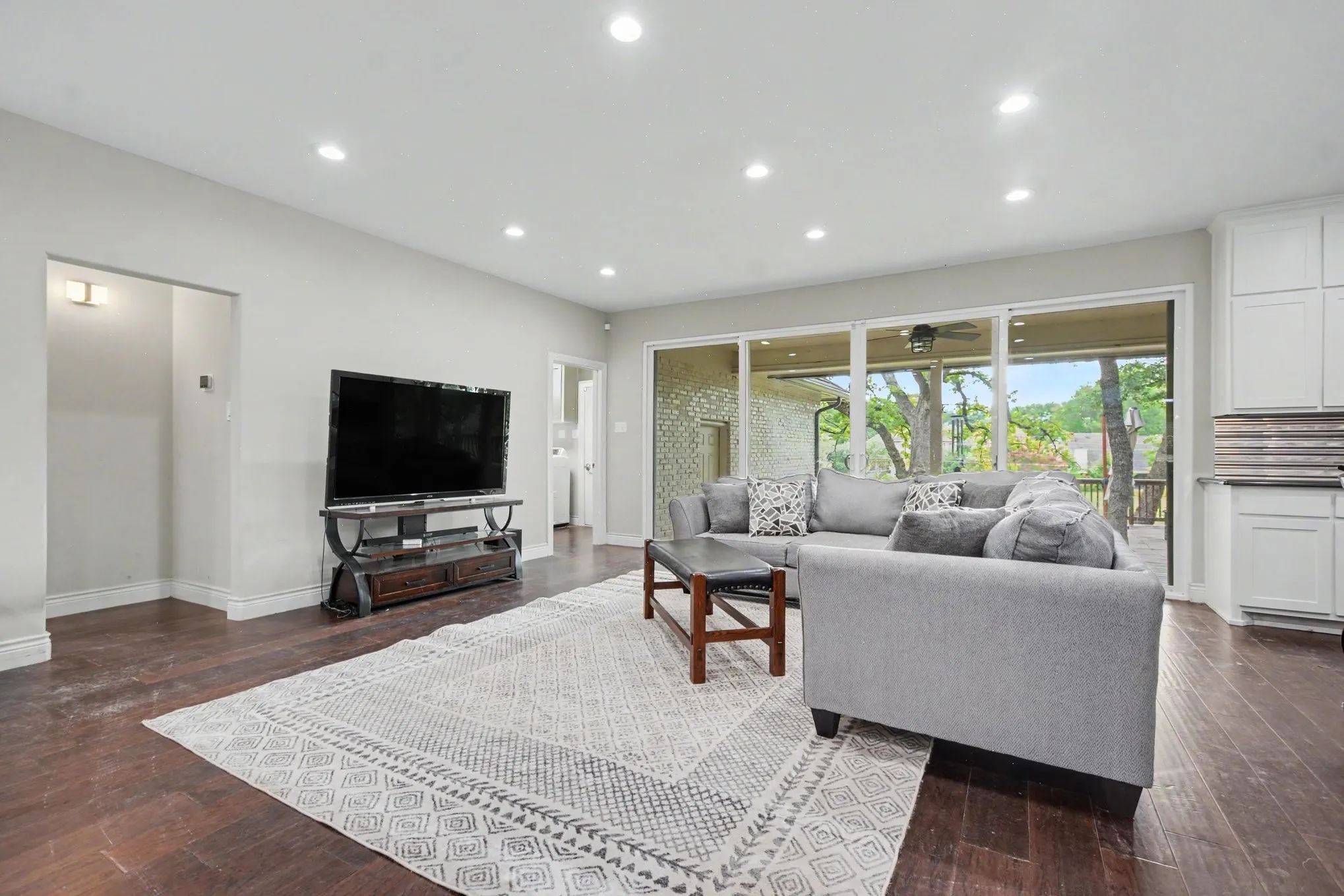 Spacious living area featuring rich wood-finish flooring, recessed lighting, and expansive glass sliding doors