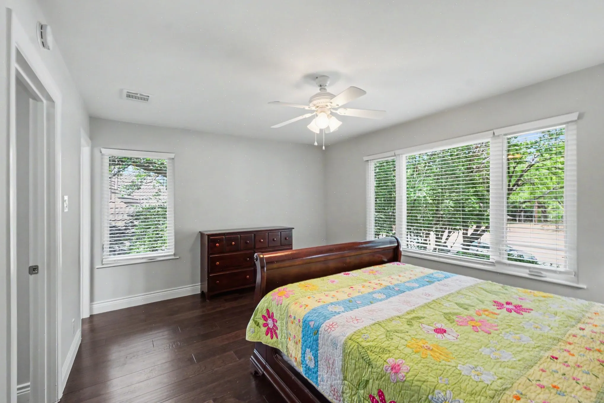 Spacious room featuring rich wood-finish flooring, light gray walls, and white trim