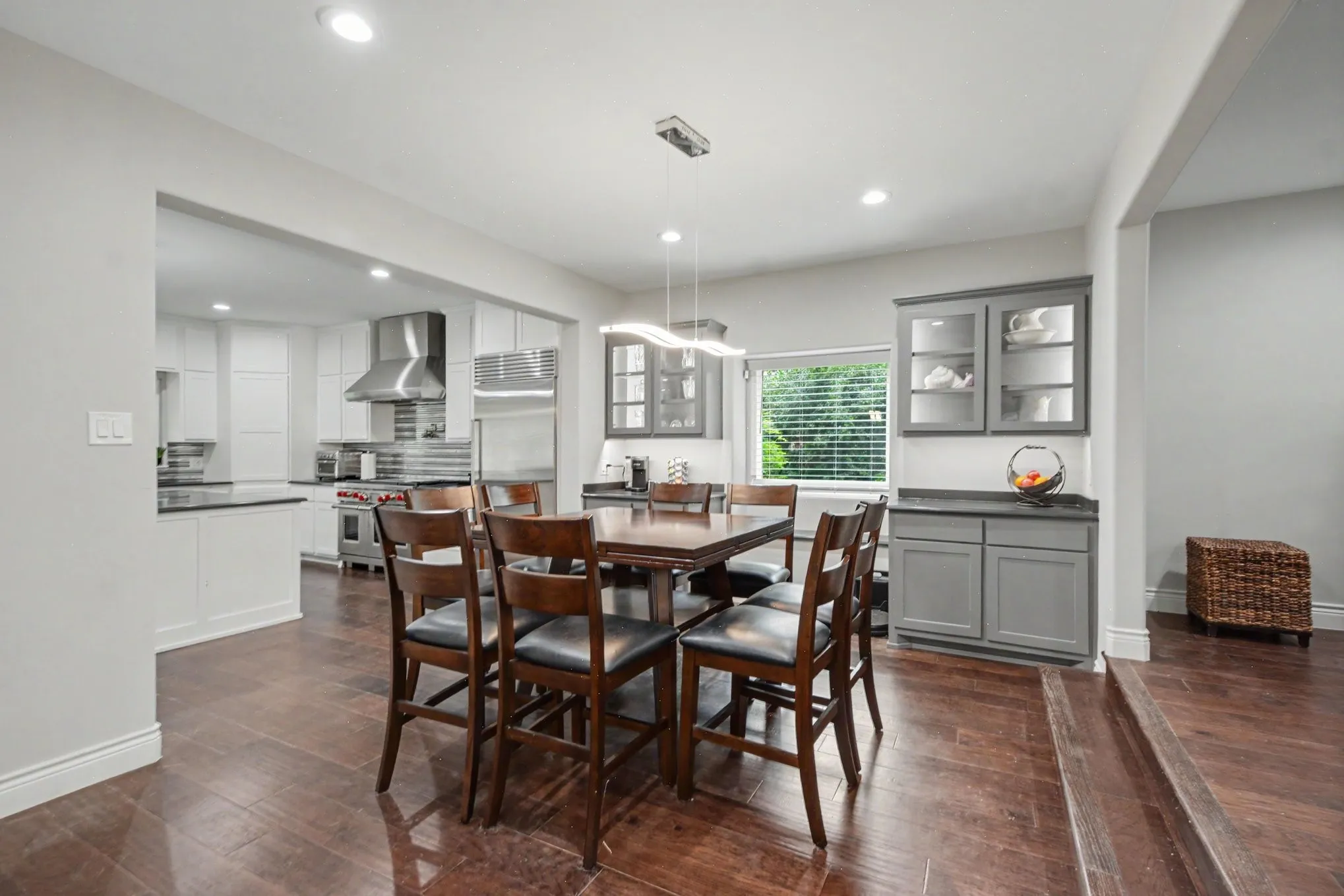 Spacious dining area featuring wood-finish flooring, recessed lighting, and a contemporary linear chandelier