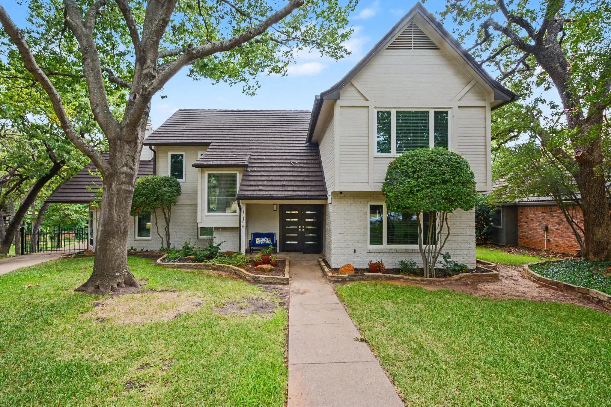 Two-story residence featuring a tile roof, light-colored siding, and brick accents