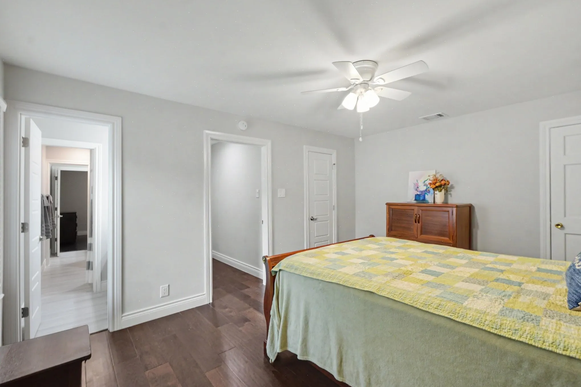 Bedroom featuring dark wood-finish flooring, light-colored walls, white trim, and a ceiling fan with integrated lighting