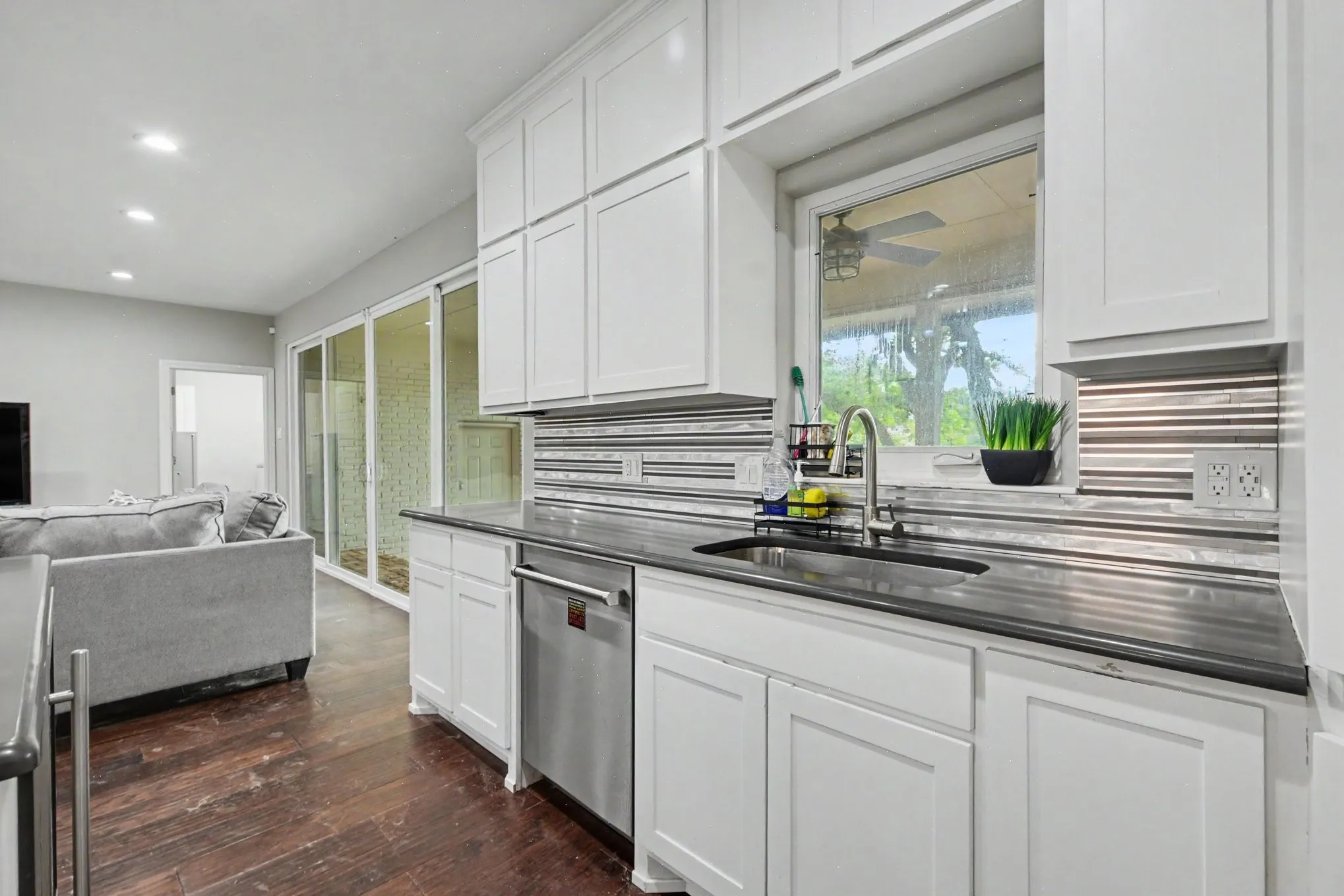 Kitchen features white shaker cabinetry, a dark countertop, and a stainless steel undermount sink with a gooseneck faucet