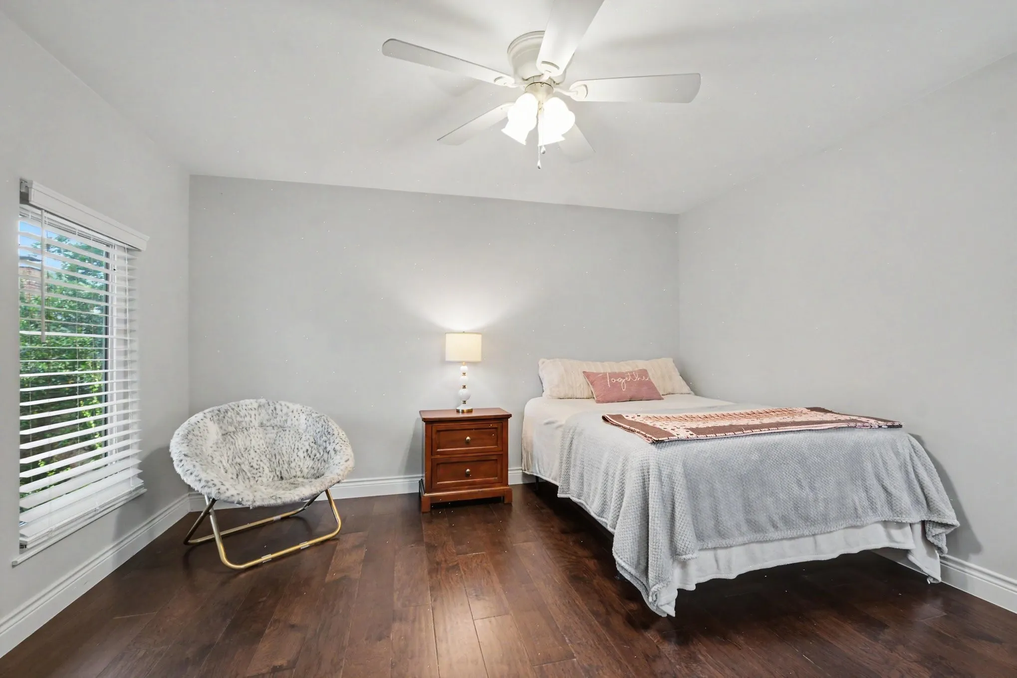 Room featuring dark wood-finish flooring, light-colored walls, and a ceiling fan with integrated lighting