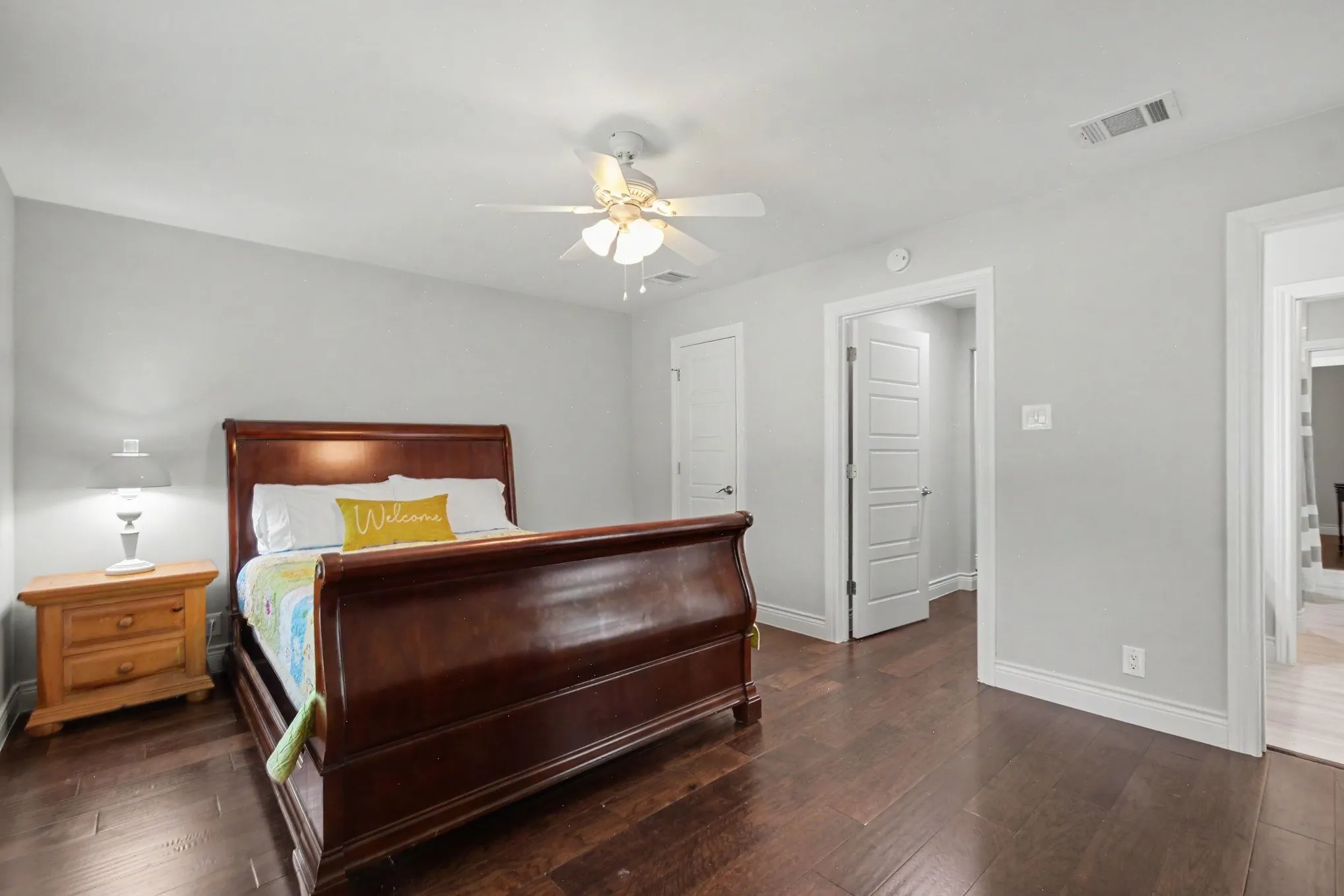 Spacious room featuring rich wood-finish flooring, light gray walls, and white trim