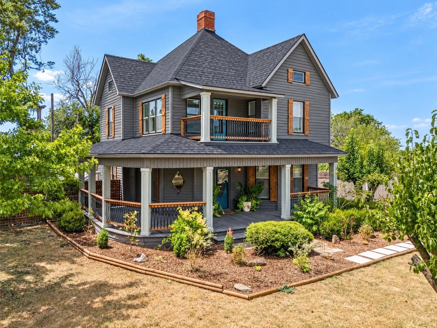 Multi-level exterior with dark gray siding, a wraparound porch, and a second-story balcony