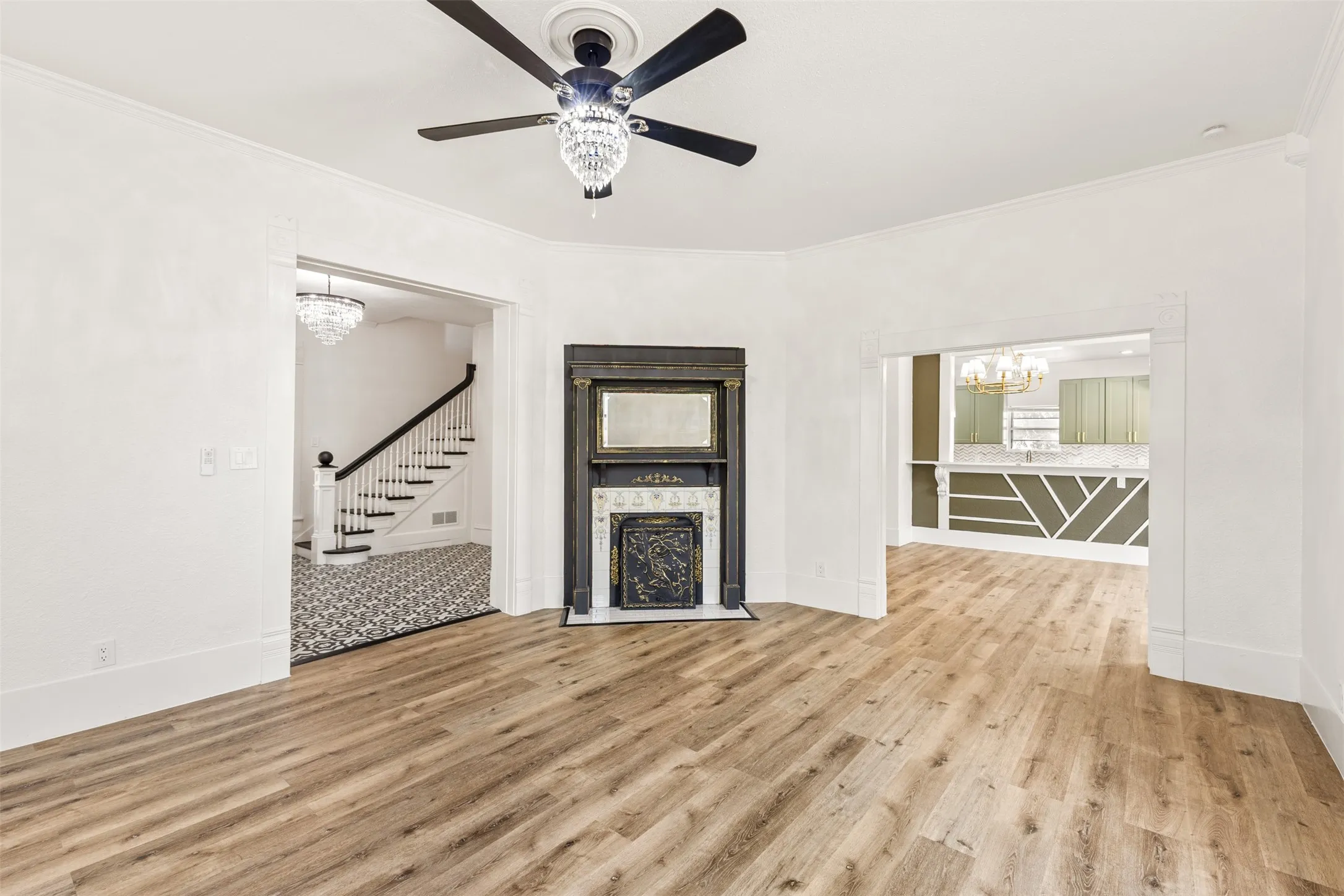 Spacious open living area showcasing wood-finish flooring, ceiling fan with integrated lighting, and multiple windows providing natural light
