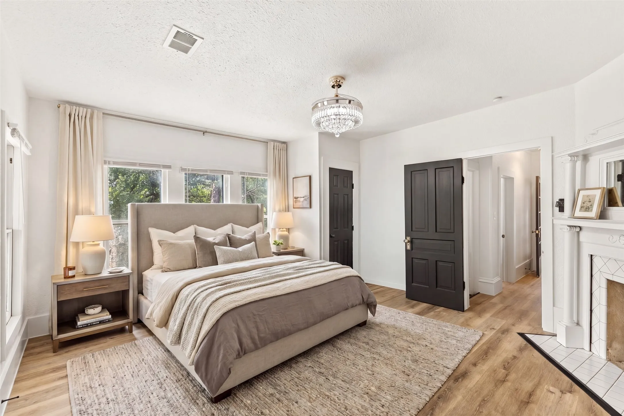 Hardwood-style flooring, white walls, decorative chandelier, dark paneled doors, and a fireplace with tile surround